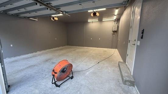 Garage with dark walls and bare concrete floor before coating