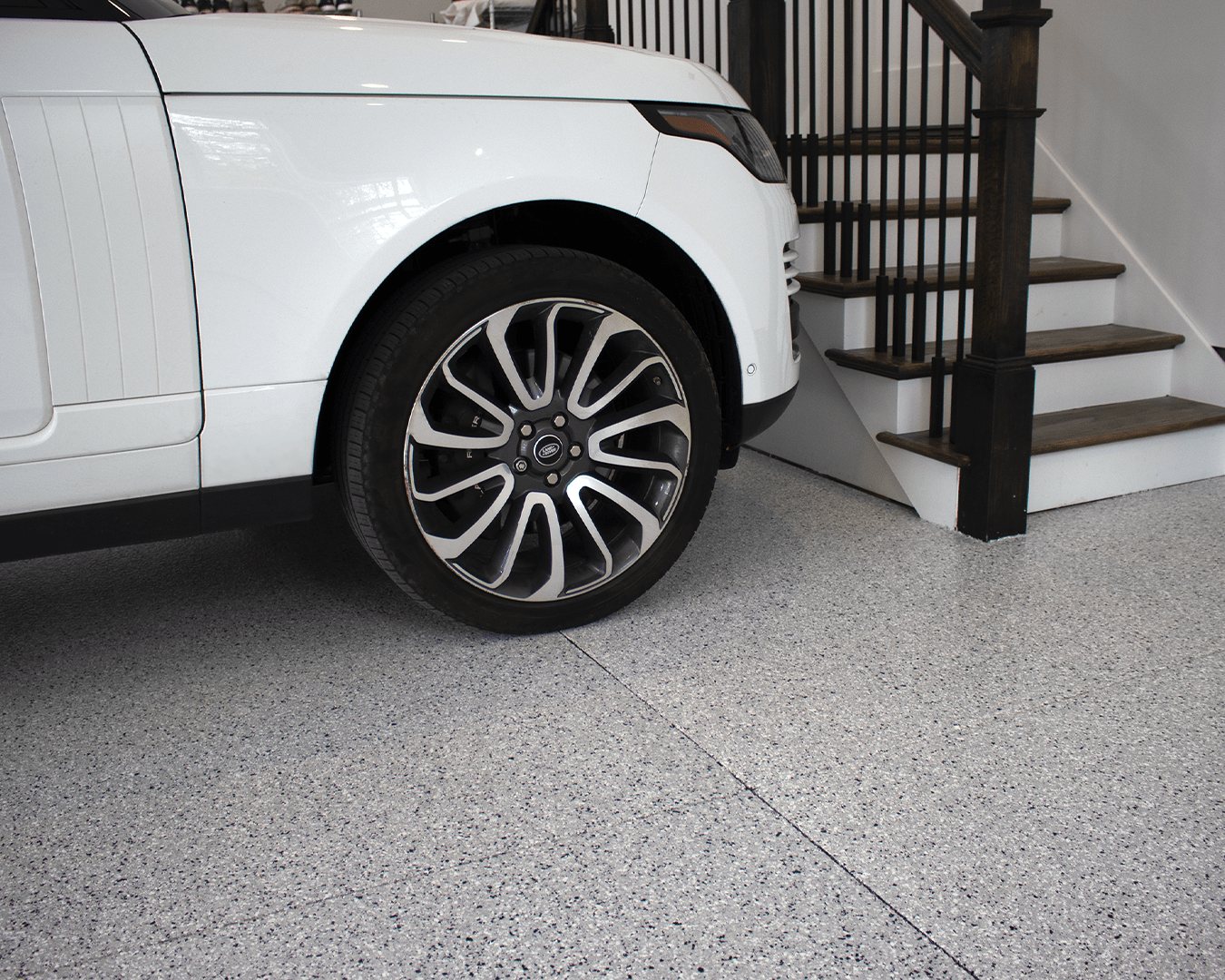 SUV parked on light gray flake garage floor by stairs